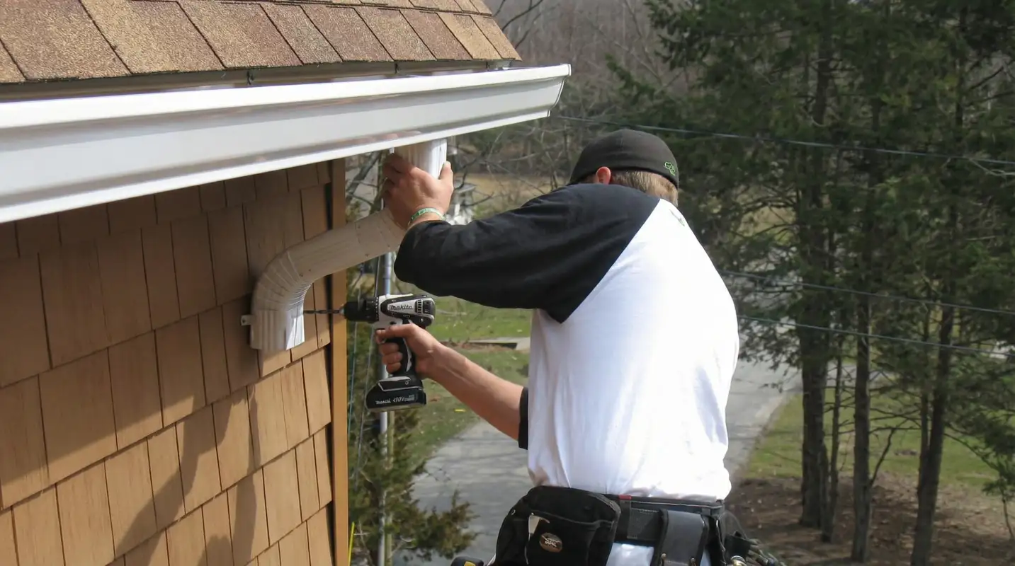 Professional contractor installing tan vinyl siding panels on a residential home exterior in Duluth, MN